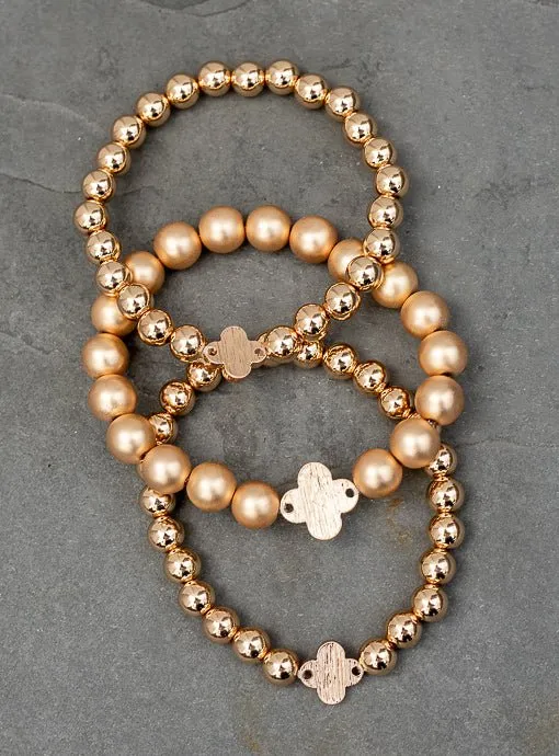 Matte And Shiny Gold Three Piece Bracelet Set With Clover